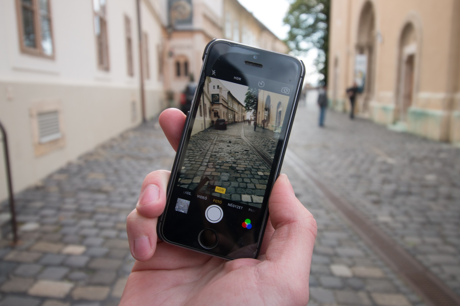 Imagem de uma pessoa segurando um celular em frente a uma rua. Na tela do celular aparece uma imagem dessa mesma rua smart city